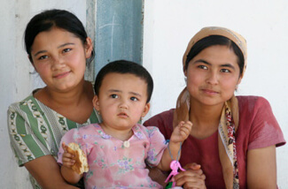 Mary E. Frederickson, Young weavers with a "lap baby" on break in the factory courtyard, Uzbekistan, 2006.
