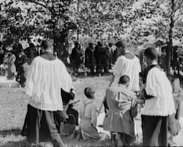 Russell Lee, Library of Congress, Prints & Photographs Division FSA-OWI Collection Reproduction Number: LC-USF33-011901-M2 DLC, Catholic priests blessing members of their congregation, New Roads, Louisiana, 1938.