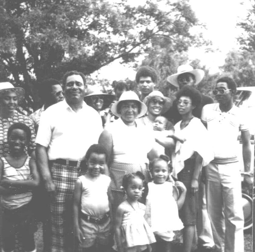 A black and white photograph depicting Ed Scott and his family smiling for the camera.