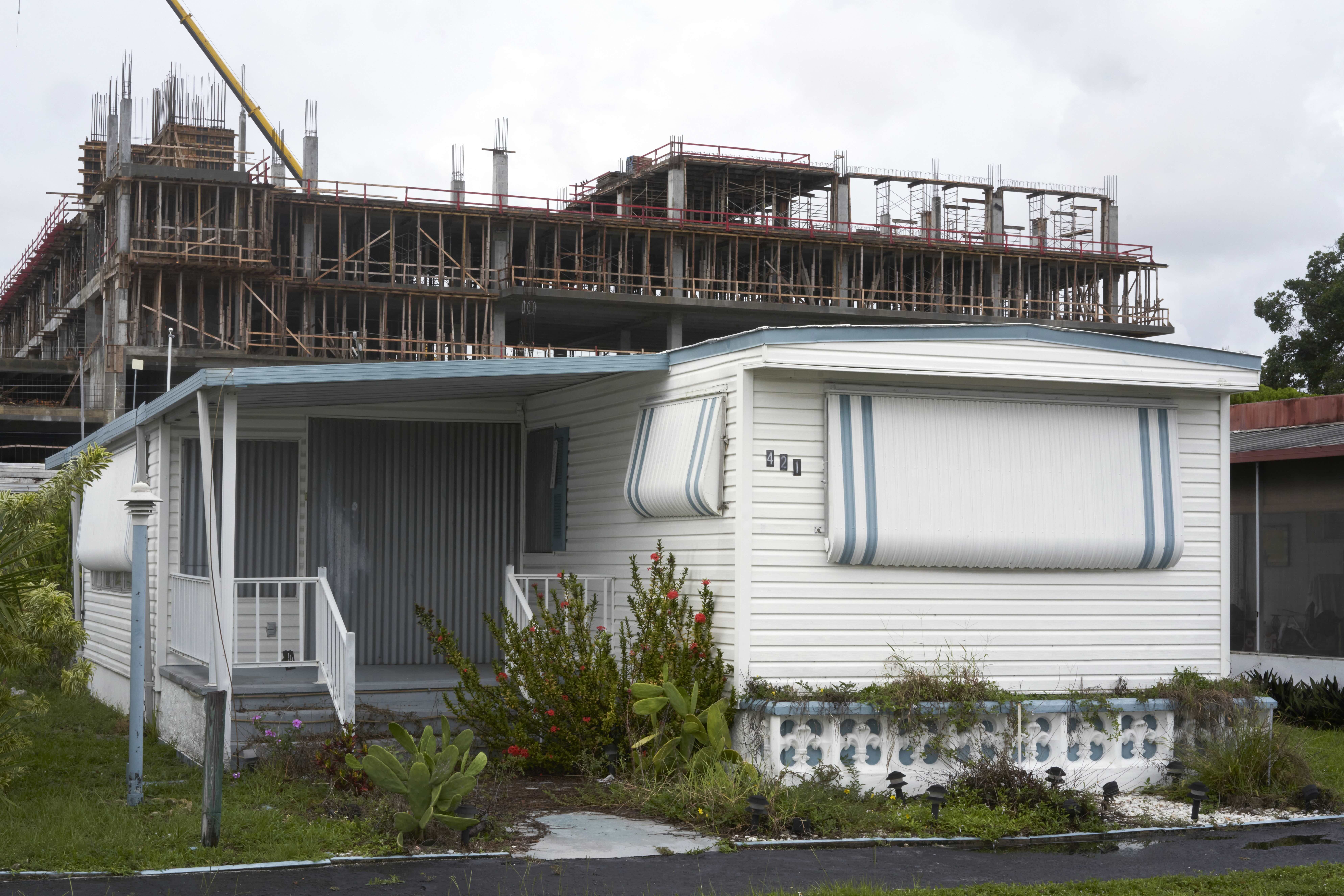 White house trailer being devoured by rebar of new building.