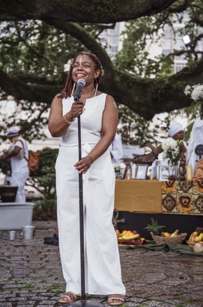 Asali DeVan Ecclesiastes in white dress in front of microphone.